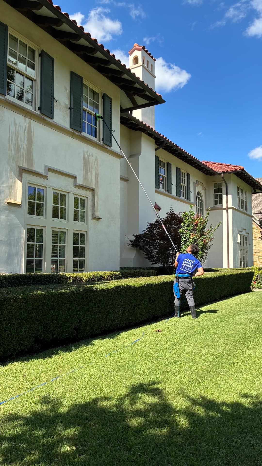 Shine & Bright technician cleaning second-story windows with a water-fed pole